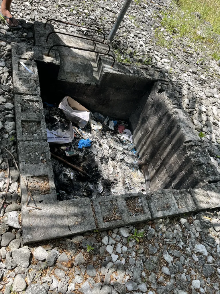 Ärzte ohne Grenzen in Kiribati mit Blick auf eine Feuergrube, in der Abfall verbrannt wird.