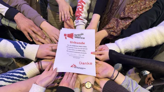 Viele Hände der Schüler:innen halten die Urkunde von Ärzte ohne Grenzen