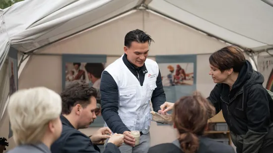 Arzt Daniel Uy lädt Besucher:innen ein, therapeutische Fertignahrung zu kosten.