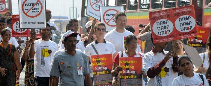 Menschen marschieren mit Schildern, um gegen die Vorgehensweise von Novartis zu protestieren.