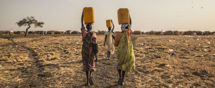 Drei Frauen tragen Wasser im Vertriebenenlager in Melut.