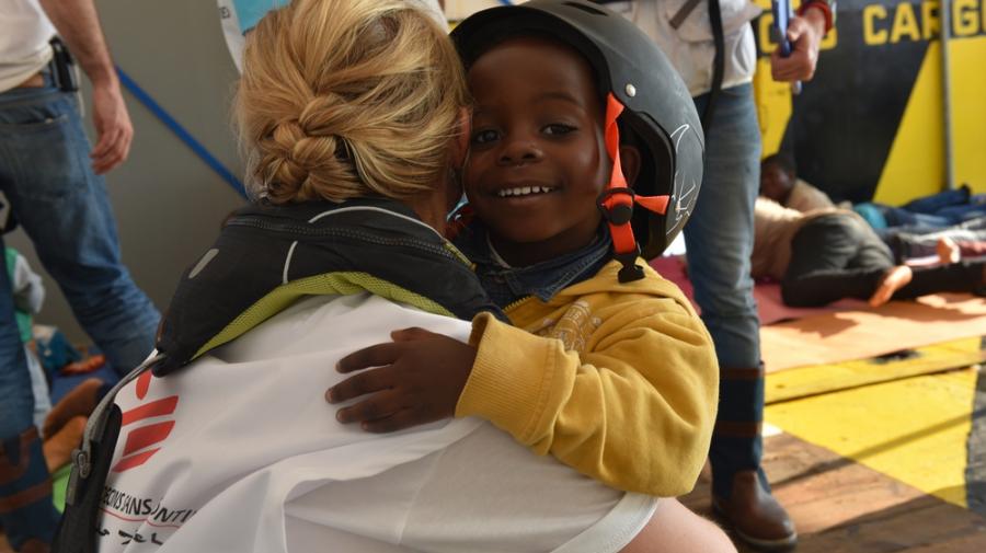 Gerettetes Kind umarmt eine Einsatzmitarbeiter von Ärzte ohne Grenzen auf Rettungsschiff