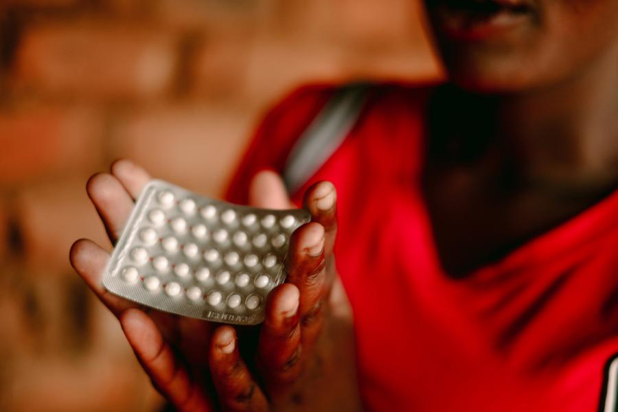 Eine Frau in Malawi hält eine Packung der Pille hoch.
