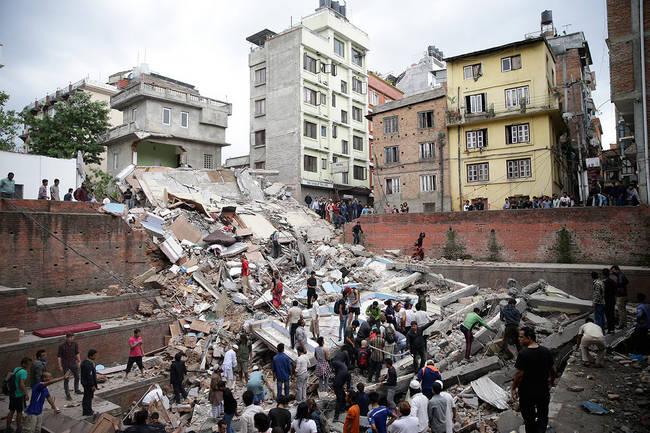 Menschen suchen in den Trümmern eines eingestürzten Hauses nach Überlebenden  nach einem Erdbeben. 