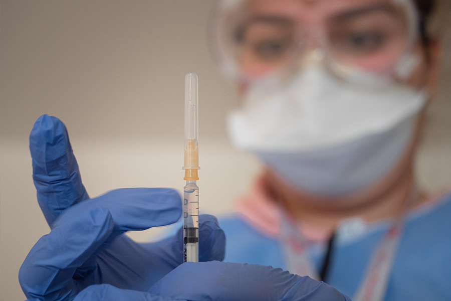 Eine Krankenpflegerin hält eine Spritze mit COVID-19 Impfstoff in der Hand