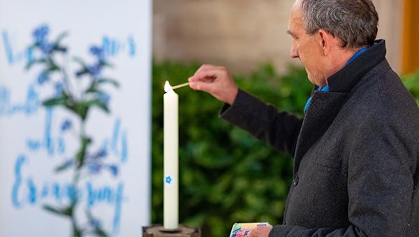 Günter Lutschinger, Initiator von Vergissmeinnicht, entzündet eine Kerze im Gedenken an Testamentsspenderinnen und -spender.