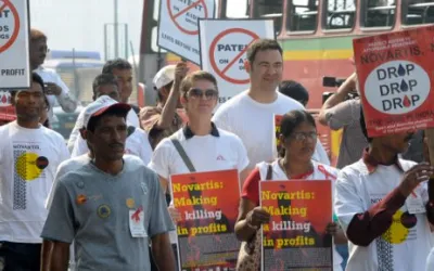 Menschen marschieren mit Schildern, um gegen die Vorgehensweise von Novartis zu protestieren.