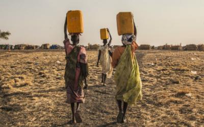 Drei Frauen tragen Wasser im Vertriebenenlager in Melut.
