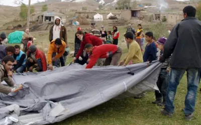 Mehrere Menschen bauen zusammen ein winterfestes Zelt auf.