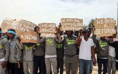 Tripolis, Libyen, 04.04.2019: Während eines Besuchs von UN-Generalsekretär Antonio Guterres im Flüchtlingslager Ain Zara in Tripolis halten Migranten Protestschilder in die Höhe.