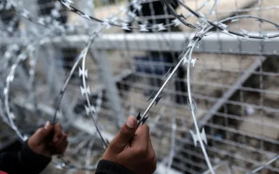 Ein Kind aus Afghanistan hält sich am Grenzzaun zwischen Griechenland und Mazedonien fest.