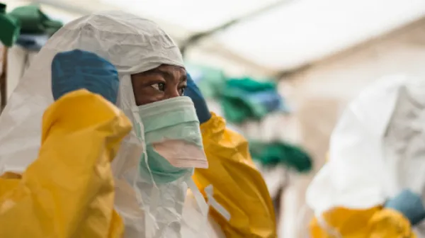 Bevor die medizinischen Teams im Isolationsbereich Ebola-PatientInnen versorgen können, muss die entsprechende Schutzkleidung angelegt werden.
