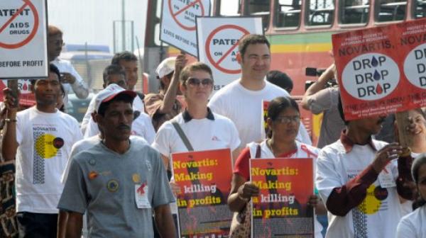 Menschen marschieren mit Schildern, um gegen die Vorgehensweise von Novartis zu protestieren.