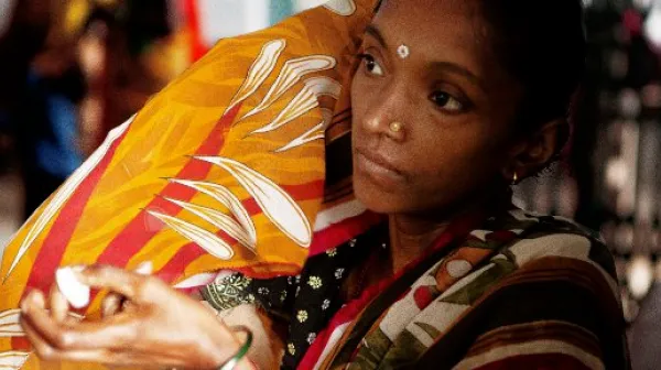 Eine Mutter trägt ihr Baby und hält das Medikament in der Hand