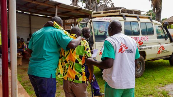 Two MSF medical staff help a patient
