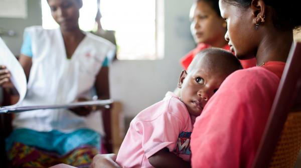 A mother and child sitting for a checkup at Pusalota health centre.