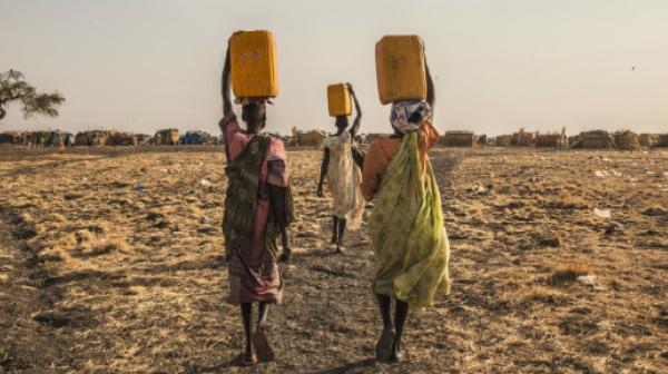 Drei Frauen tragen Wasser im Vertriebenenlager in Melut.