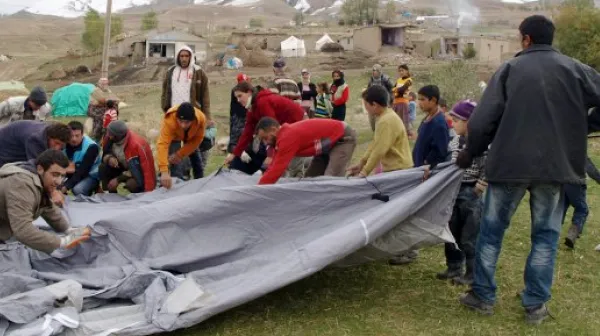 Mehrere Menschen bauen zusammen ein winterfestes Zelt auf.