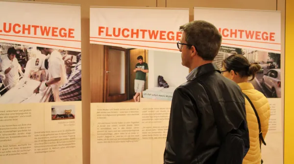 BesucherInnen sehen sich die Ausstellung Fluchtwege von Ärzte ohne Grenzen an.