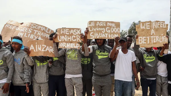 Tripolis, Libyen, 04.04.2019: Während eines Besuchs von UN-Generalsekretär Antonio Guterres im Flüchtlingslager Ain Zara in Tripolis halten Migranten Protestschilder in die Höhe.