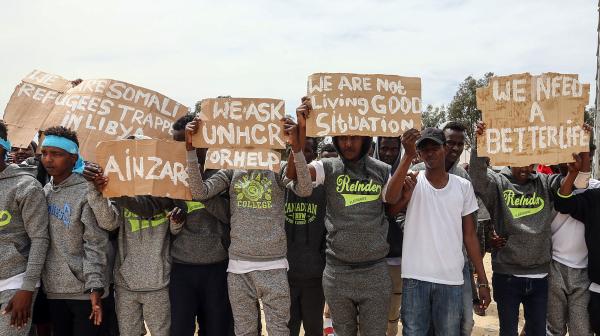 Tripolis, Libyen, 04.04.2019: Während eines Besuchs von UN-Generalsekretär Antonio Guterres im Flüchtlingslager Ain Zara in Tripolis halten Migranten Protestschilder in die Höhe.