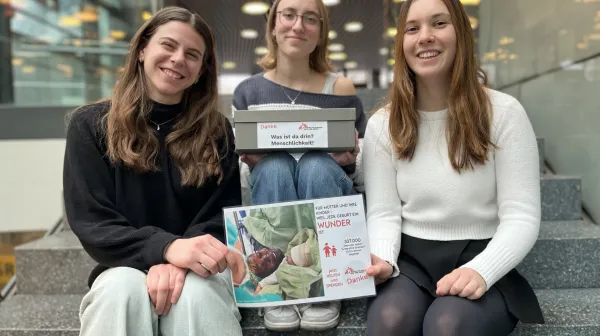 Die drei Studierenden mit Plakat und Spendenbox