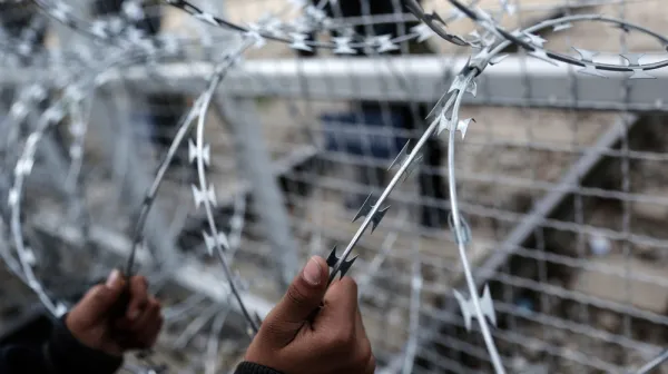 Ein Kind aus Afghanistan hält sich am Grenzzaun zwischen Griechenland und Mazedonien fest.